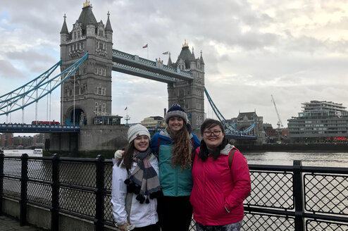 3 travelers smiling in front of bridge